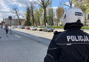 policjant w kasku motocyklowym patrzy w kierunku przejścia dla pieszych