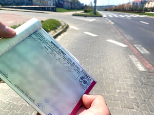 zbliżenie na bloczek mandatowy z kwotą 1500 złotych na tle przejścia dla pieszych
