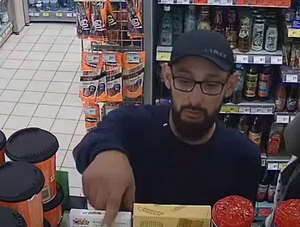 młody mężczyzna w okularach i czapce z daszkiem oraz zarostem na twarzy - jeden ze sprawców kradzieży w sklepie