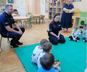 Policjanci rozmawiają z dziećmi siedząc na dywanie