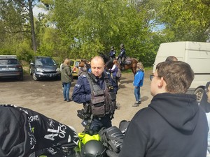 Policjant przy stoisku z policyjnym sprzętem rozmawia z młodzieżą