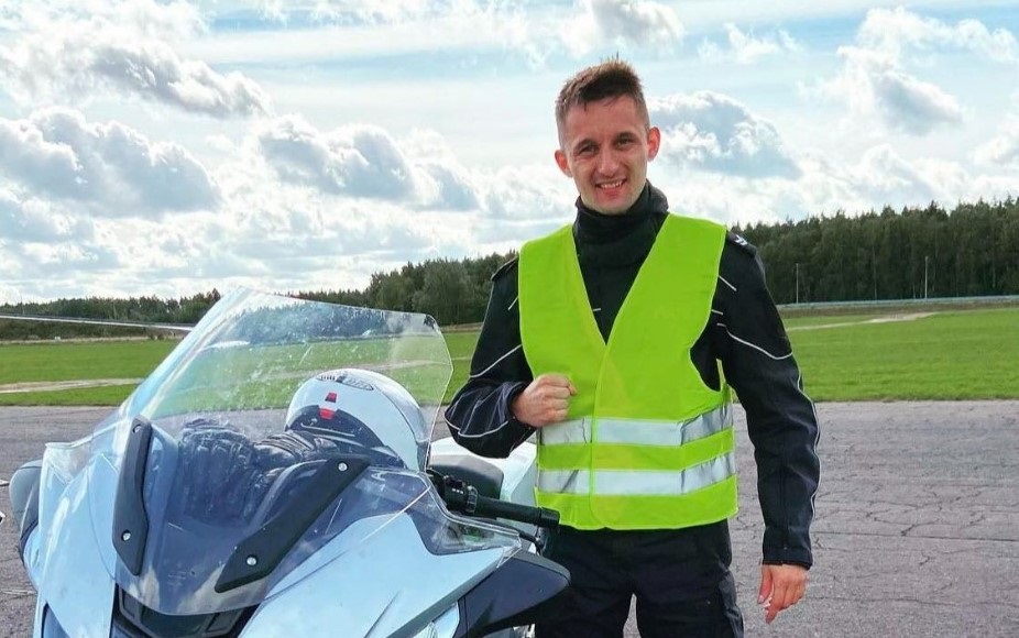 na zdjęciu policjant w mundurze stoi przy motocyklu