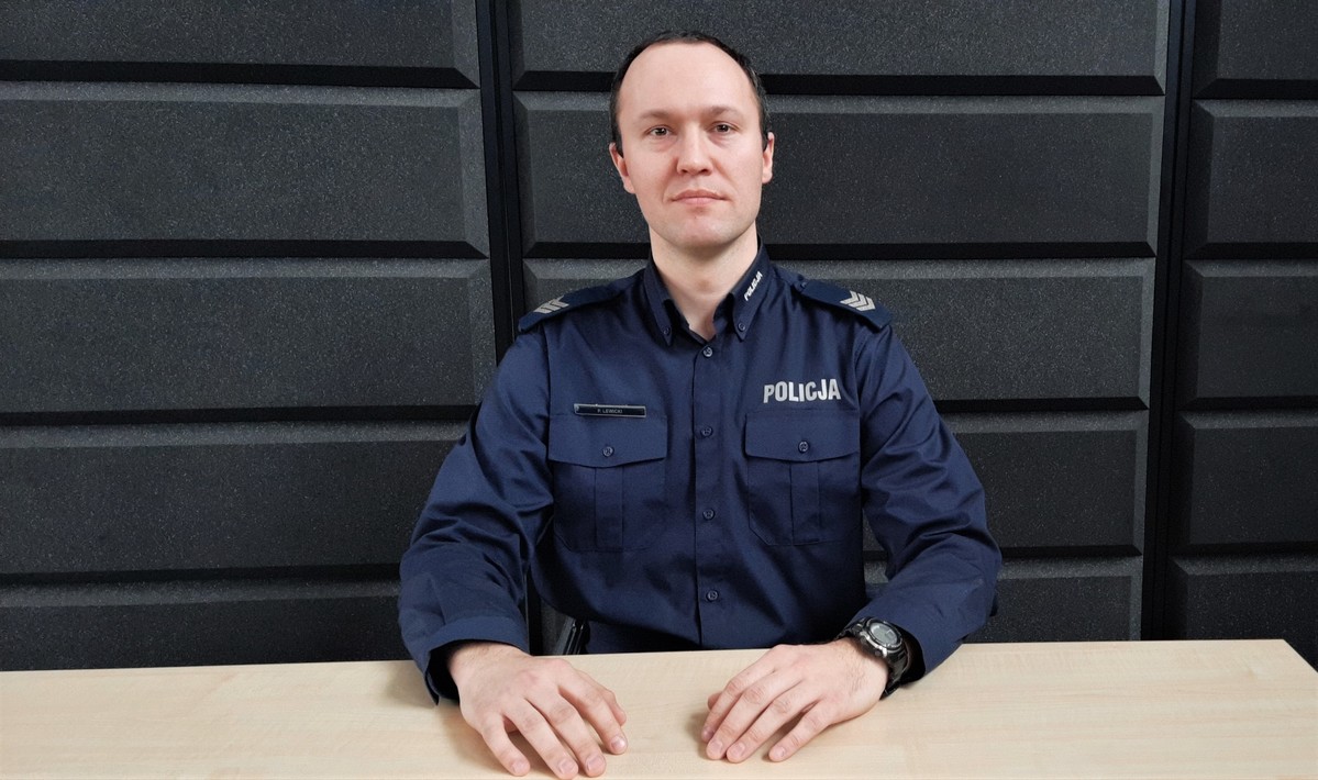 Umundurowany policjant siedzi przy biurku
