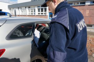 Policjant umieszcza zatrzymanego w radiowozie.