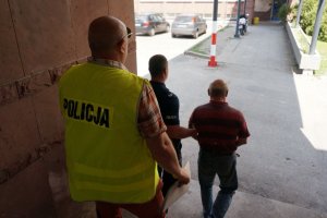 Policjanci prowadzą zatrzymanego.