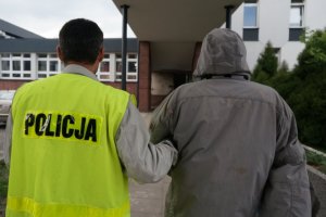 Policjant prowadzi zatrzymanego.