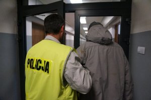 Policjant prowadzi zatrzymanego.