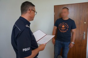 Policjant odbiera wyróżnienie z rąk komendanta.