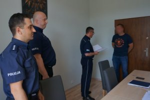 Policjant odbiera wyróżnienie z rąk komendanta.