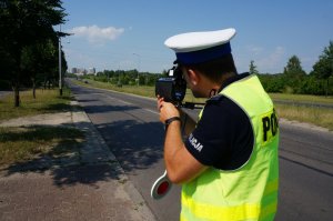 Policjant z miernikiem prędkości na drodze.