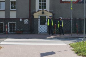 Policjanci lustrują drogę przy szkołę.