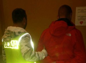 Policjant prowadzi zatrzymanego.