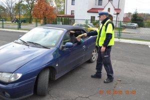 policjant przekazuje kamizelkę odblaskową