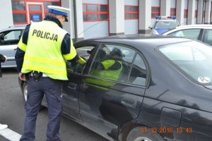 Policjant wręcza kamizelkę odblaskową