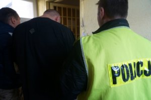 Policjanci prowadzą zatrzymanego.