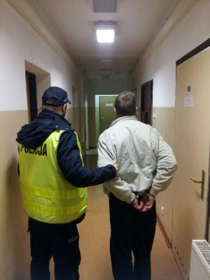 policjant prowadzi zatrzymanego.
