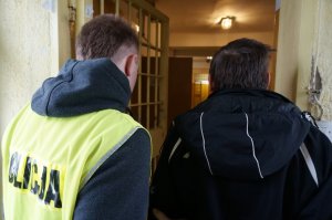 Policjant prowadzi zatrzymanego.