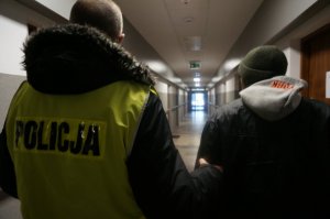 Policjant prowadzi zatrzymanego.