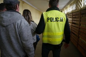 Policjant prowadzi zatrzymanego.