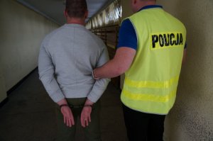 Policjant prowadzi zatrzymanego.