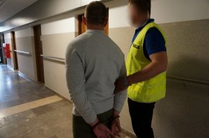 Policjant prowadzi zatrzymanego.