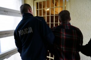 Policjant prowadzi zatrzymanego.