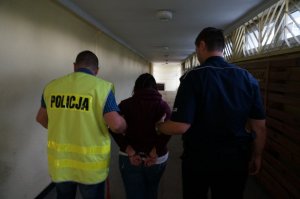 Policjanci prowadzą zatrzymaną.