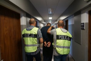 Policjanci prowadzą zatrzymanego.