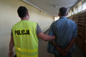 Policjant prowadzi zatrzymanego.