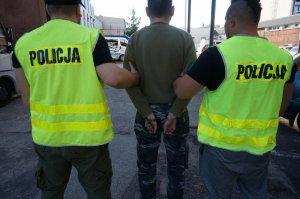 Policjanci prowadzą zatrzymanego.