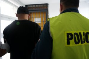 Policjanci prowadzą zatrzymanego.
