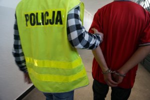Policjant prowadzi zatrzymanego.