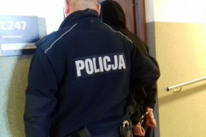 Policjant prowadzi zatrzymanego.
