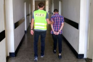 Policjant prowadzi zatrzymanego.