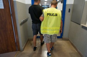 Policjant prowadzi zatrzymanego.