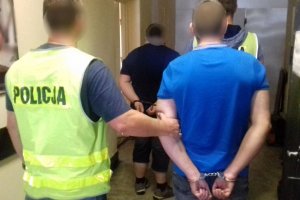 Policjanci prowadzą zatrzymanych.