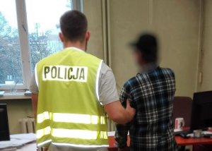 Policjant prowadzi zatrzymanego.
