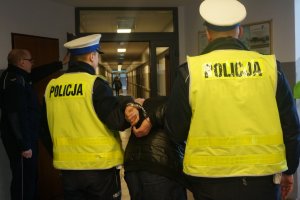 Policjanci prowadzą zatrzymanego.