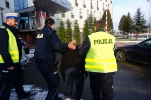 Policjanci prowadzą zatrzymanego.