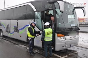 dwóch mundurowych w kamizelkach odblaskowych rozmawia z kierowca autokaru stojąc przy drzwiach od kierowcy