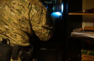 policjant z latarką w ręku dokonujący sprawdzenia w szafce