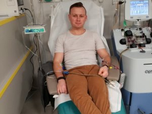 mężczyzna siedzący na fotelu z podpiętą aparaturą do pobrania krwi