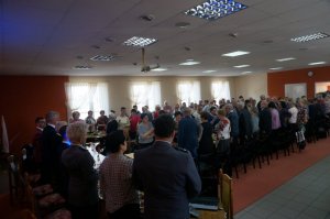 zebranie seniorów - seniorzy i przedstawiciele policji oraz samorządu lokalnego siedzą przy stołach