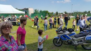 policjanci na motocyklach i radiowozem na festynie. w tle widać wiele osób uczestników festynu