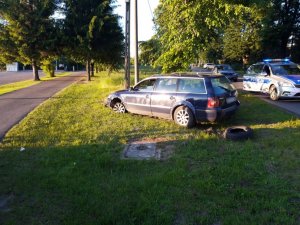 Samochód porzucony przez sprawców na poboczu oraz policyjne radiowozy oznakowane