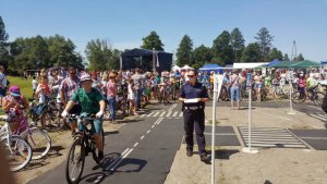 policjantka w mundurze na miasteczku rowerowym przygląda się dzieciom jeżdżącym na rowerach