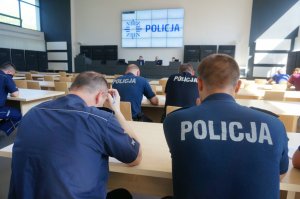 policjanci siedzą w ławkach na auli