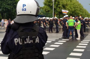 na pierwszym planie tył bluzy policjanta z napisem policja, w tle policjanci z prewencji