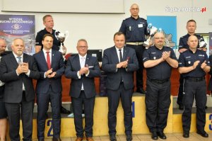 policjanci stoją na podium, przed nimi stoją w szeregu policjanci i mężczyźni w garniturach pozują do zdjęcia