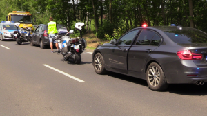 nieoznakowany radiowóz policyjny na sygnałach stoi za zatrzymanym samochodem osobowym obok policjant